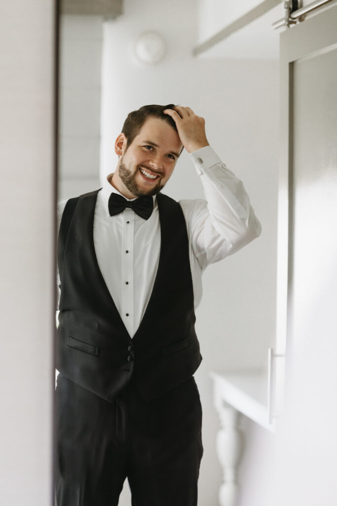 A groom getting ready fixing his hair in a mirror before his wedding day at Ellis Preserve wedding venue in Newtown Square, PA.