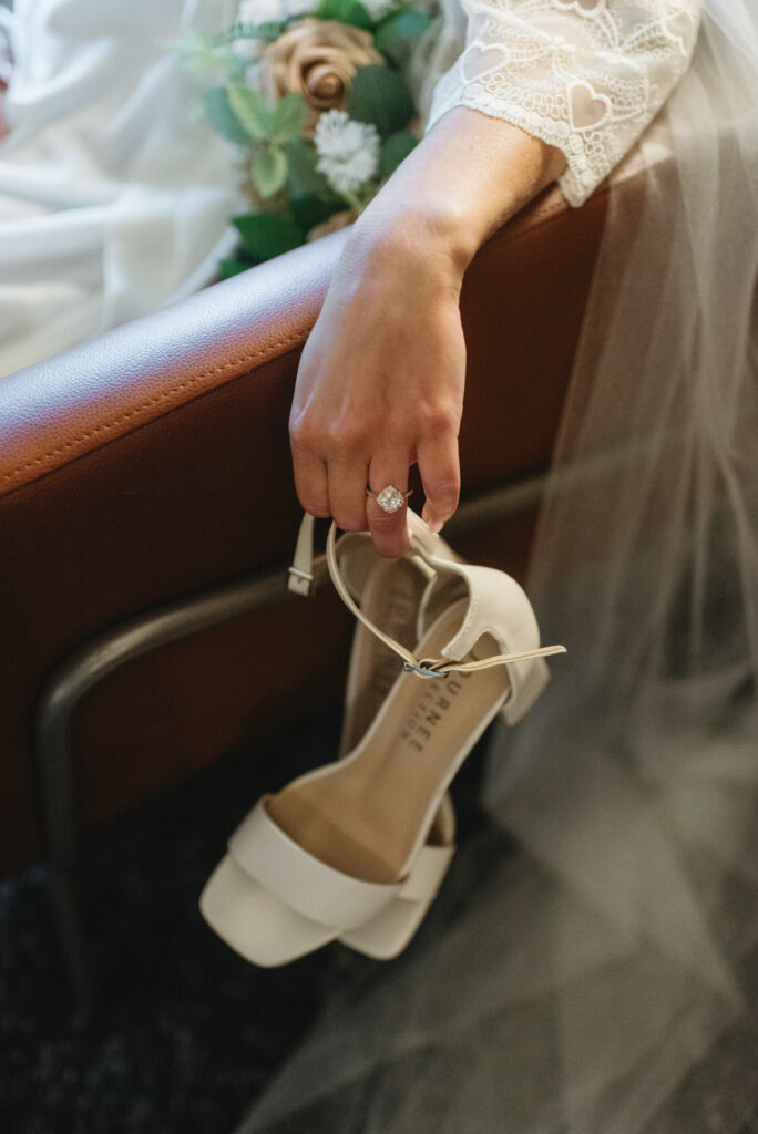 Riverdale Manor wedding. Bride holding her cream wedding heels and showing off her engagement ring on the morning of her wedding day.