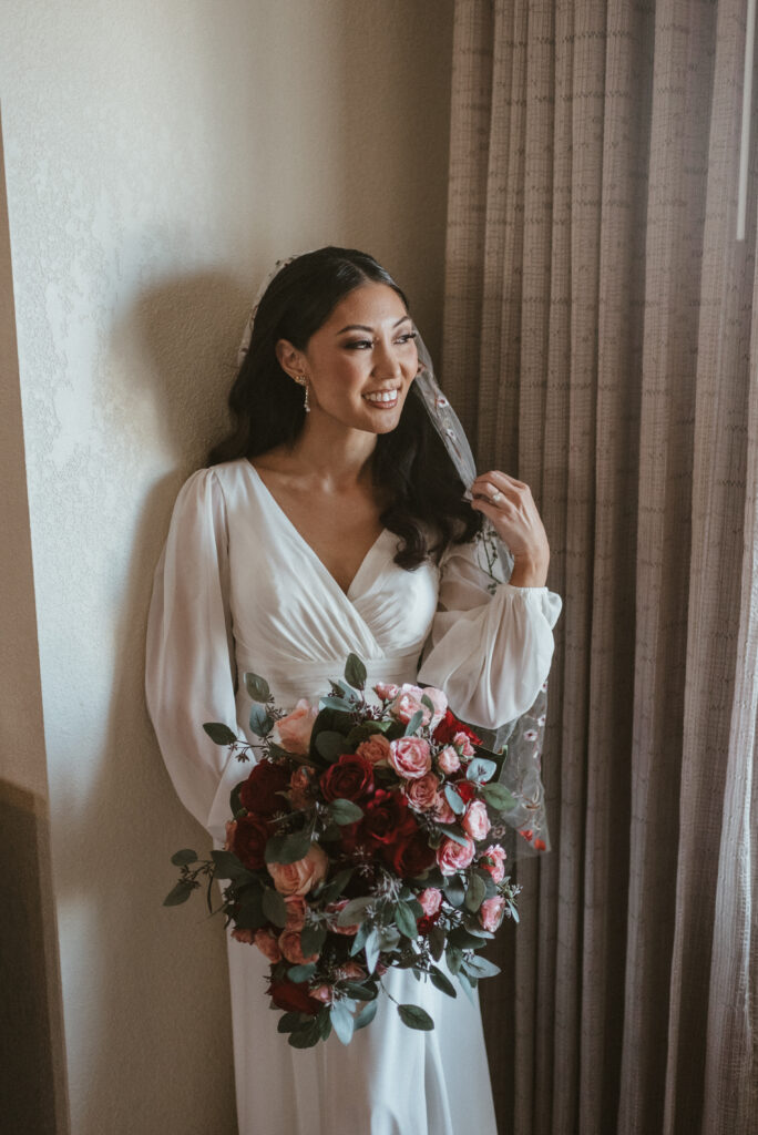 A bride posing with her bouquet and veil.