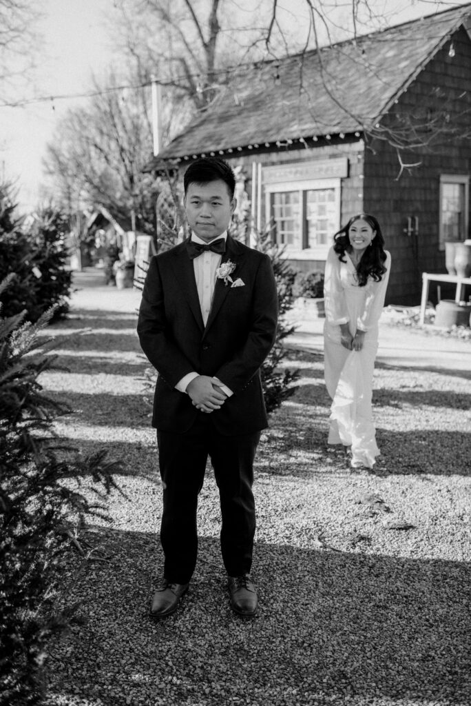 A bride walking up behind her groom in anticipation of seeing each for the first look on their wedding day. Terrain at Styers