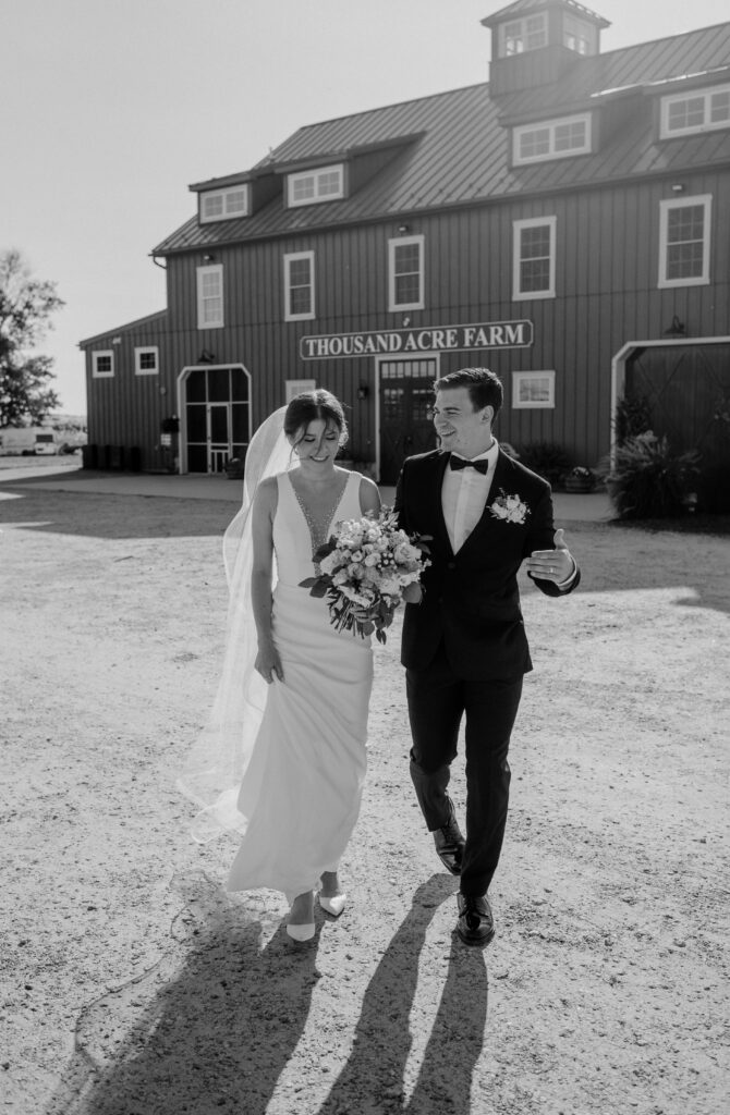 A bride and groom walking in front of their wedding venue at Thousand Acre Farm in Middletown, Delaware.