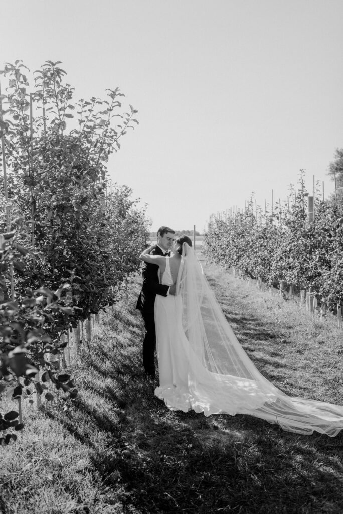 Bride and groom in an apple orchard at Thousand Acre Farm wedding venue in Middletown, Delaware.