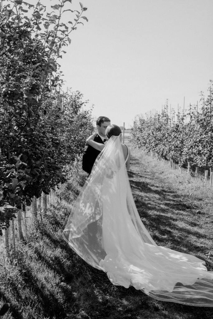 Bride and groom in an apple orchard at Thousand Acre Farm wedding venue in Middletown, Delaware.