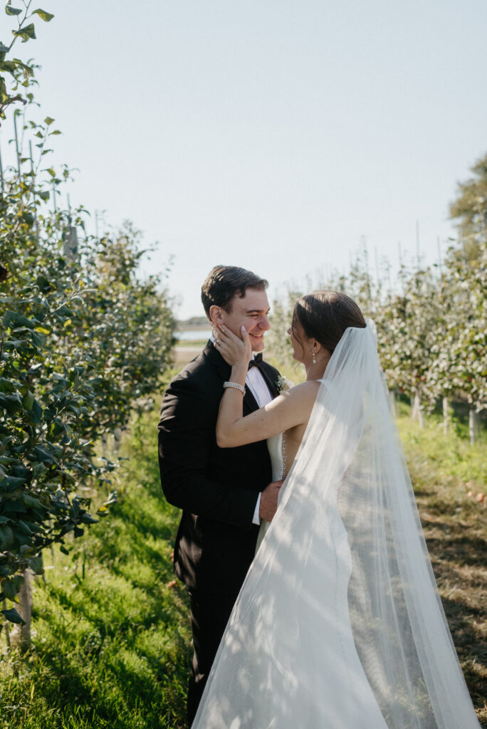 Bride and groom in an apple orchard at Thousand Acre Farm wedding venue in Middletown, Delaware.