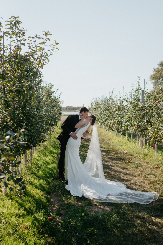 A bride and groom kiss in an apple orchard on their wedding day in Middletown, Delaware at Thousand Acre Farms.