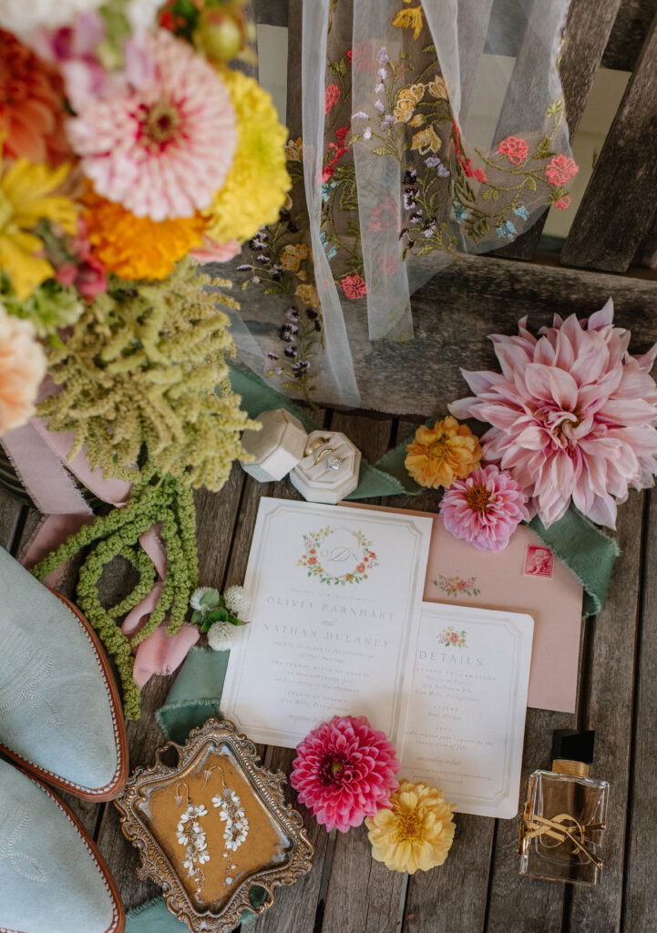 Colorful details for wedding at Terrain Gardens. Wildflowers of pinks, yellows, and oranges. Wildflower veil. Gold perfume. Blue cowboy boots. Invitations. Gold plate with wildflower earings. Gold ring box.