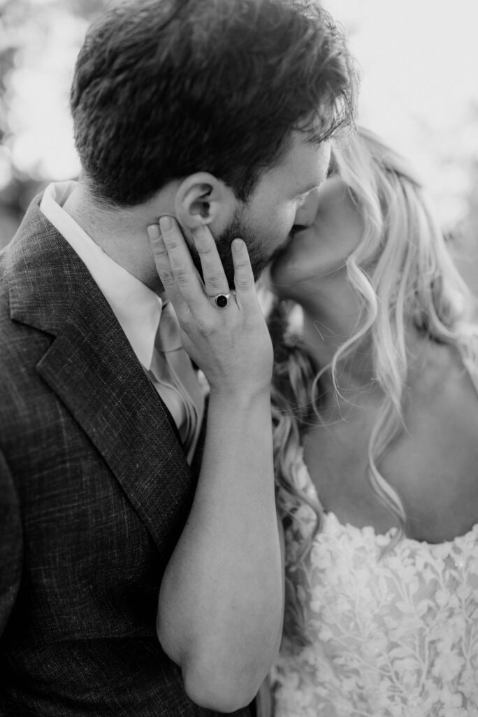 Bride kissing her groom detail of hand and ring in black and white at the Inn at Grace Winery in Glen Mills, PA. 